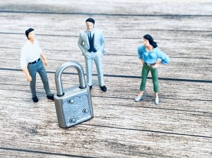 議論する人々を表すミニチュア人形と解決すべき問題を示す錠前